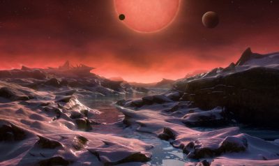 This artist’s impression shows an imagined view from the surface one of the three planets orbiting an ultracool dwarf star just 40 light-years from Earth that were discovered using the TRAPPIST telescope at ESO’s La Silla Observatory. These worlds have sizes and temperatures similar to those of Venus and Earth and are the best targets found so far for the search for life outside the Solar System. They are the first planets ever discovered around such a tiny and dim star. In this view one of the inner planets is seen in transit across the disc of its tiny and dim parent star.